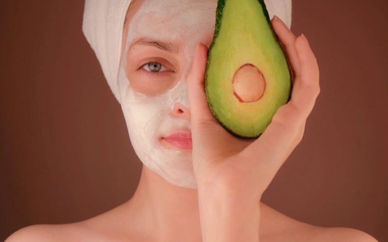 woman with white face mask holding green fruit